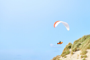 Colorful Paraglider Flying Above Dunes