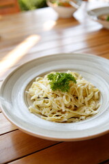 Fettuccine Alfredo is a wide ribbon of pasta. It's topped with plenty of grated cheese and garnished with fresh parsley and basil. The sauce is light in color and creamy in texture.