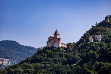 Castillo medieval sobre colina boscosa en los Alpes italianos