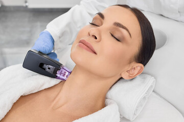 Beautiful woman doing radio frequency neck and body lifting. RF lifting procedure in beauty salon with a beautician