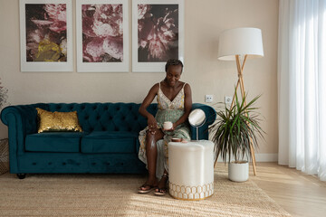 Young black woman applying skincare cream on leg