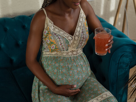 Expecting Mother Relaxes on a Couch While Enjoying Vitamin Drink