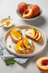 Toasted bruschetta with peach, nectarine, cream cheese or ricotta and honey on a plate on a light background