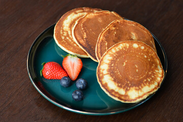 Yummy Pancakes with strawberries and blueberries on a plate.