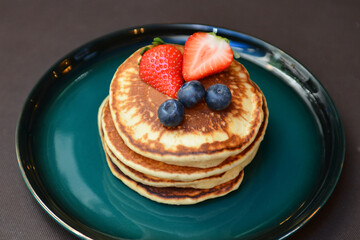 Yummy Pancakes with strawberries and blueberries on a plate.