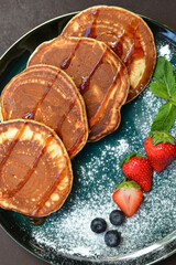 Pancakes with fresh berries and sugar powder on a black background