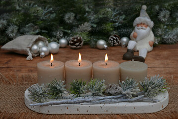Adventsdekoration für den dritten Advent : Dekoration mit vier Adventskerzen vor einer weihnachtlichen Kulisse mit Platz für Text.	
