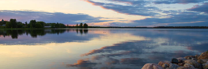 Beautiful evening panorama of the lake. Clouds are reflected in the water. Sunset. Lake Valdayskoye, Valday (Valdai), Novgorod region, Russia.