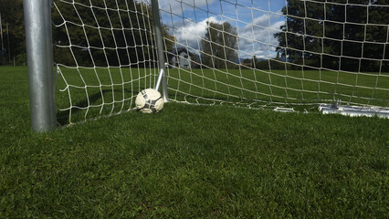 Obraz premium Football goals on green grass and red sports field with nature in the background, outdoor sports playground