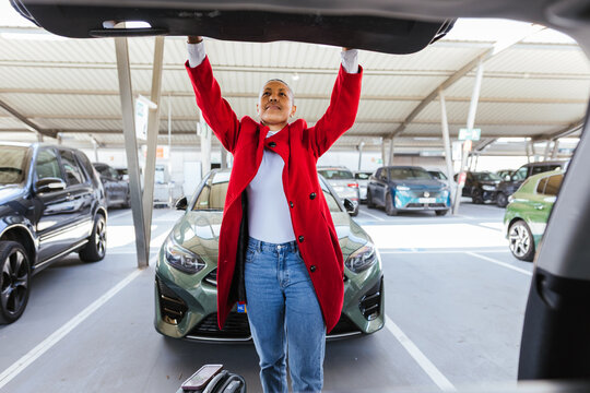 a woman closing the trunk of her car in the parking lot