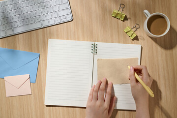 Person Writing on Notebook by Coffee in Bright Workspace Setting