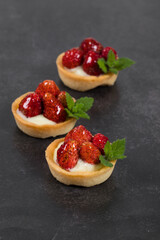 Small Round Strawberry tartlets. Dark gray background. Close up	