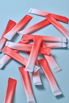 sachets scattered on a pastel blue surface for packaging concepts