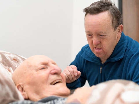 Adult man with down syndrome sharing smile with his ederly father 
