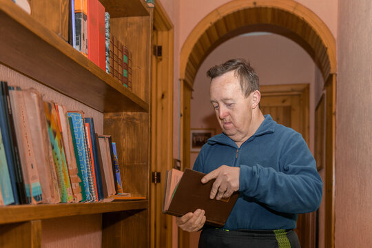 Man with Down syndrome takes a book from the bookshelf