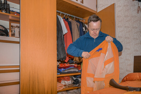 Man with Down Syndrome Organizing Clothes in Wardrobe 