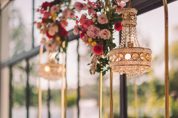 Elegant chandeliers adorned with colorful flowers create a stunning atmosphere in a bright, airy space during a joyful celebration