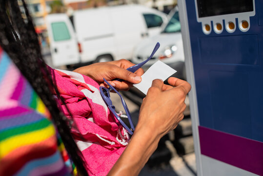 Examining a Parking Receipt at a Meter in a Vibrant Urban Area