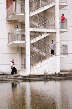 Four Asian women on the outdoor ladder of an old building