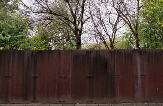 Closeup of rusty textured iron wall with woods in the background