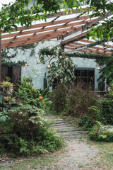 A cozy outdoor cafe surrounded by lush green garden, wooden pergola walkway, rustic architecture, natural ambiance, peaceful seating area and relaxing vibe perfect for nature lovers