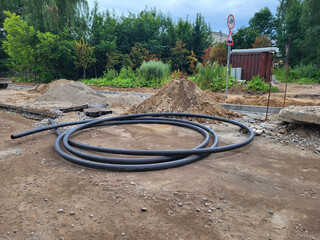 A construction site with an open trench, piles of earth, and a plastic pipe