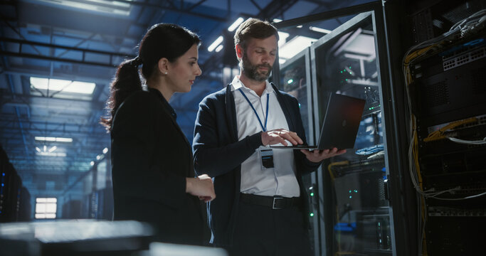 Two server specialists talk and work in data center.