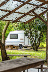 Peaceful outdoor camping site with vintage caravans parked under trees in natural setting, showcasing a serene travel lifestyle, relaxation, adventure, and sustainable eco-friendly tourism experience