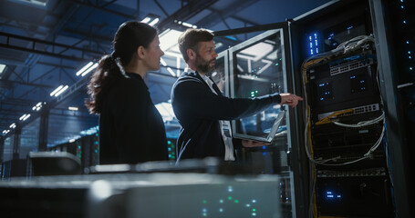 Two server specialists talk and work in data center.