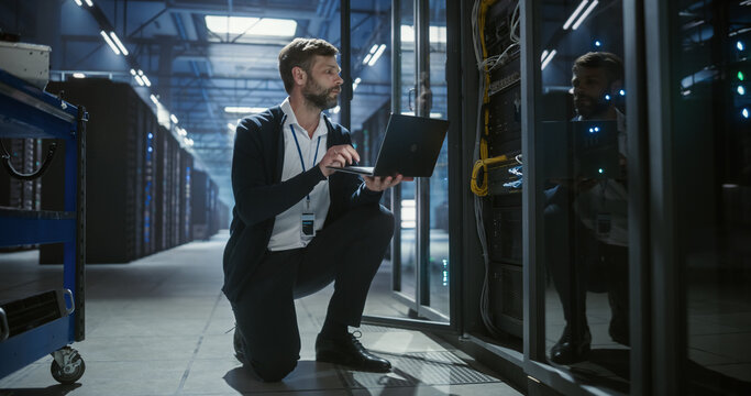 IT specialist working on laptop in data center