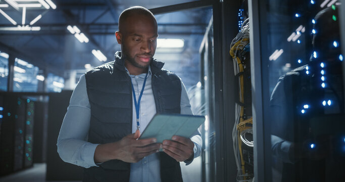Data center technician inspects server racks, checks network cables us