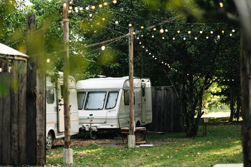 Peaceful outdoor camping site with vintage caravans parked under trees in natural setting, showcasing a serene travel lifestyle, relaxation, adventure, and sustainable eco-friendly tourism experience