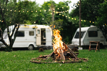 Campfire area surrounded by wooden benches and lush greenery in outdoor nature setting, perfect for group gathering, relaxation, eco-living, forest camping experience, and rustic open-air adventure