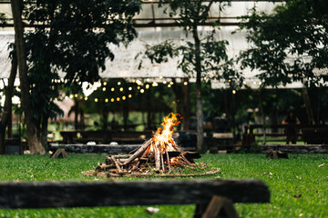 Campfire area surrounded by wooden benches and lush greenery in outdoor nature setting, perfect for...