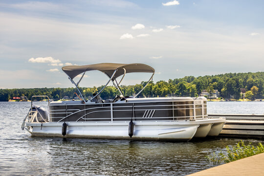 Pontoon boat at private marina dock on freshwater lake.