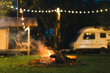 Campfire area surrounded by wooden benches and lush greenery in outdoor nature setting, perfect for group gathering, relaxation, eco-living, forest camping experience, and rustic open-air adventure