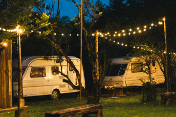Peaceful outdoor camping site with vintage caravans parked under trees in natural setting, showcasing a serene travel lifestyle, relaxation, adventure, and sustainable eco-friendly tourism experience