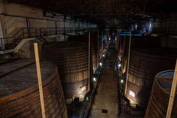 Fototapeta premium Old oak barrels for aging of natural sweet red grand cru wine Banyuls fortified dessert wine from old vines from slopes of the Catalan Pyrenees in Roussillon, France.