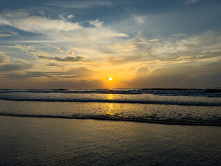 Obraz premium Sunrise Over the Ocean with Reflections on Calm Sand 