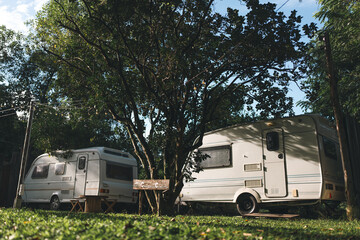 Peaceful outdoor camping site with vintage caravans parked under trees in natural setting, showcasing a serene travel lifestyle, relaxation, adventure, and sustainable eco-friendly tourism experience