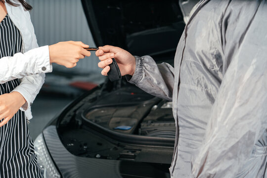 Man giving client keys to her repaired car in auto repair service