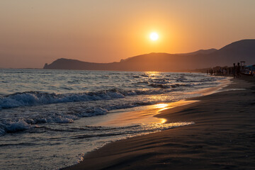 Fototapeta premium Silhouettes of swimming people on sunset in sun lights, sandy beach near Sperlonga, Lazio, italy, summer vacation
