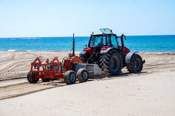 Beach maintenance work before the season, tractor cleans seaweed and loosens sand, paid beaches in...