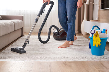 Fototapeta premium Woman cleaning the carpet with vacuum cleaner in the living room