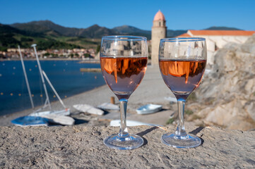 Glasses of rose Collioure AOC wine in sunlights with view on old town Collioure, colorful houses, church, castle and beaches, Occitanie, France, tourists destination