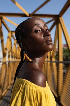 Black Model Poses Confidently on a Yellow Bridge Under Clear Blue Sky