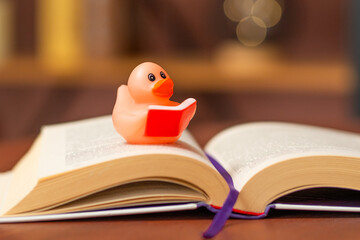 Rubber duck reading a book on a wooden table with a cozy background atmosphere