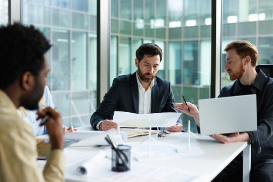 Architect telling to company leader watching physical map at meeting