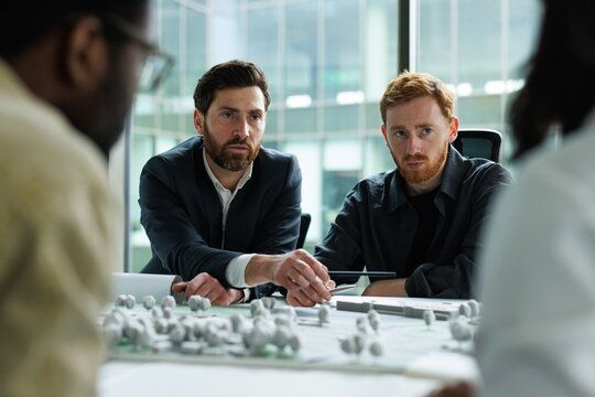 Male boss and architect looking at cropped colleagues during meeting - Powered by Adobe