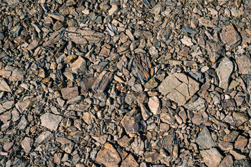 Close-up texture of broken stones and rocks on the ground. Natural background of rugged mineral surface.